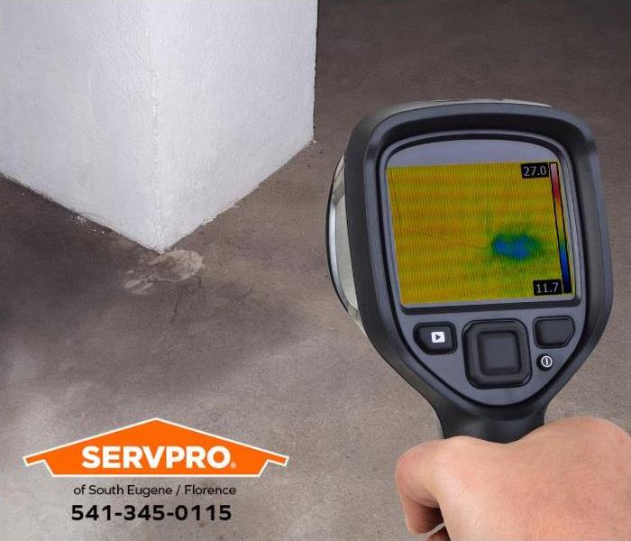 A person uses a thermal imaging device to detect hidden water damage.